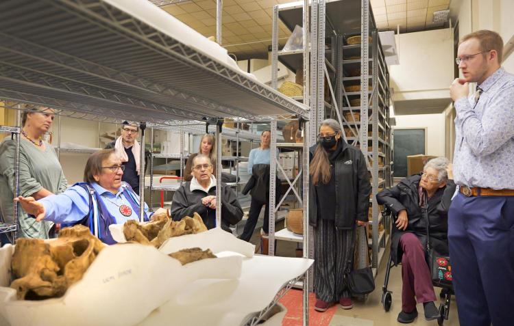 People talk gathered around shelves holding bison bones