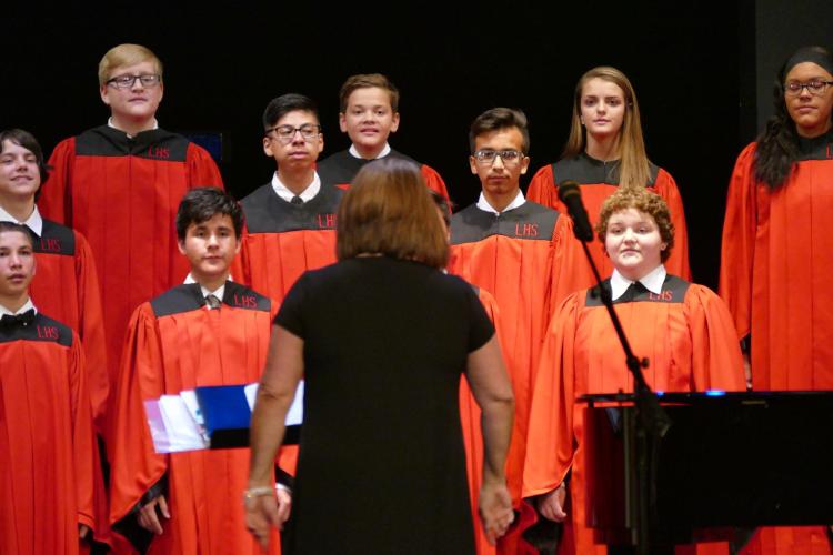 Students wear robes while singing at choir practice