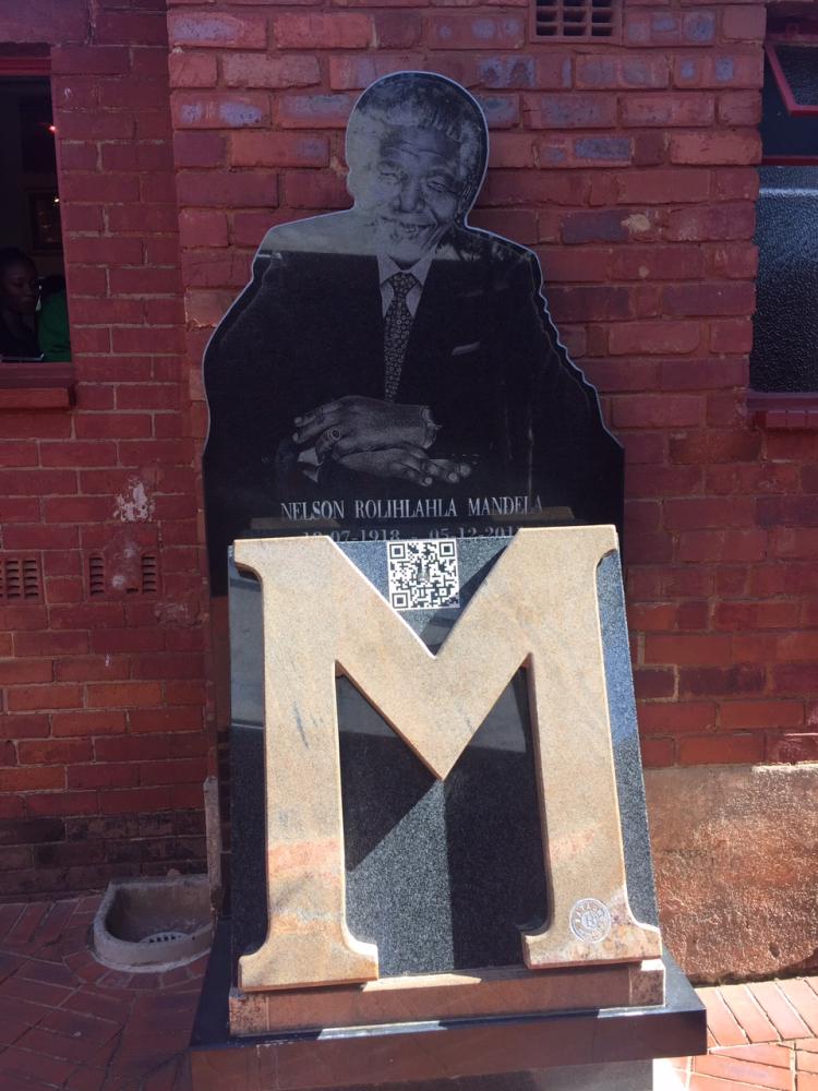 Gold letter M with cutout of Nelson Mandela