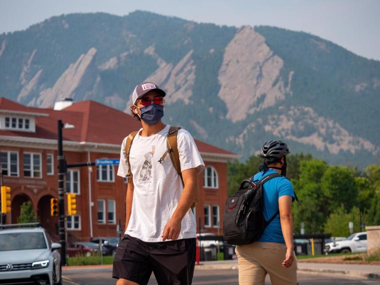 Student walking near campus while wearing a mask.
