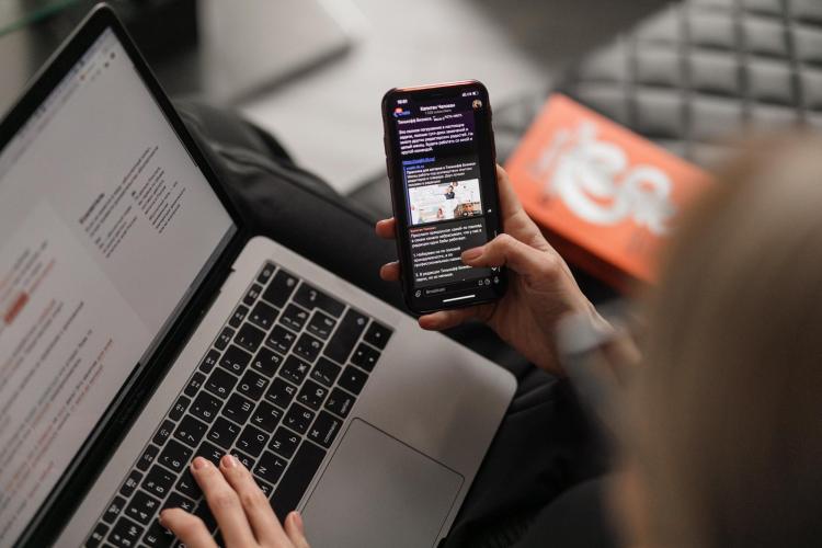 person checking phone and laptop computer