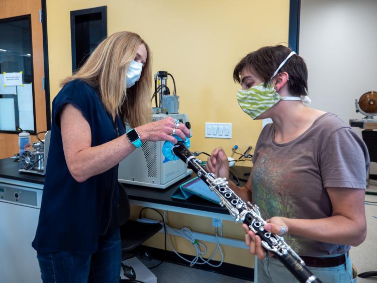 Shelly Miller (left) and graduate student Teyha Stockman (right) fit a bell cover over a clarinet.
