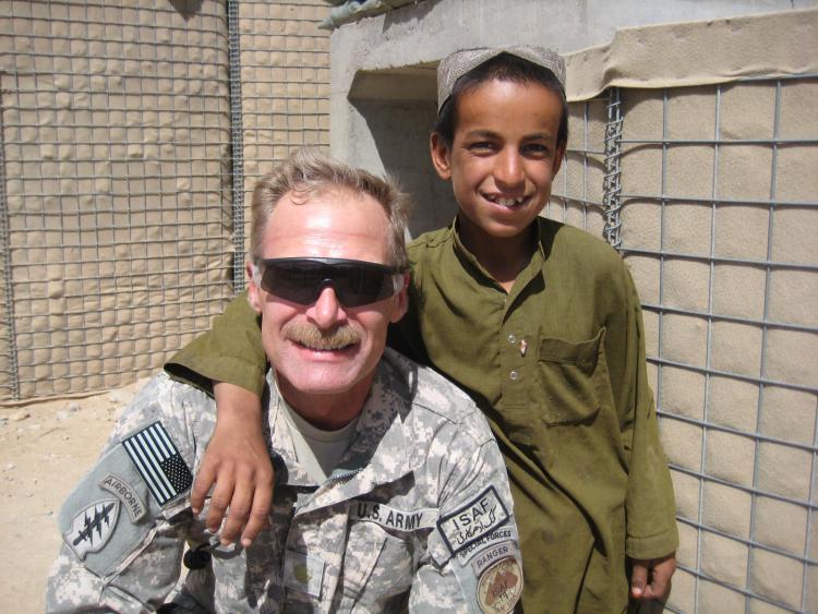 Mitch Utterback, in uniform, takes a photo arm-in-arm with a young person.