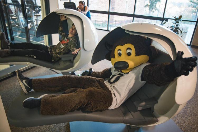 Chip and student pose for photo in nap pods on campus