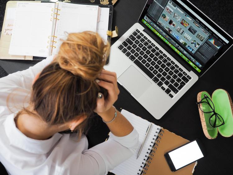 Woman with head down, stressed out over laptop computer