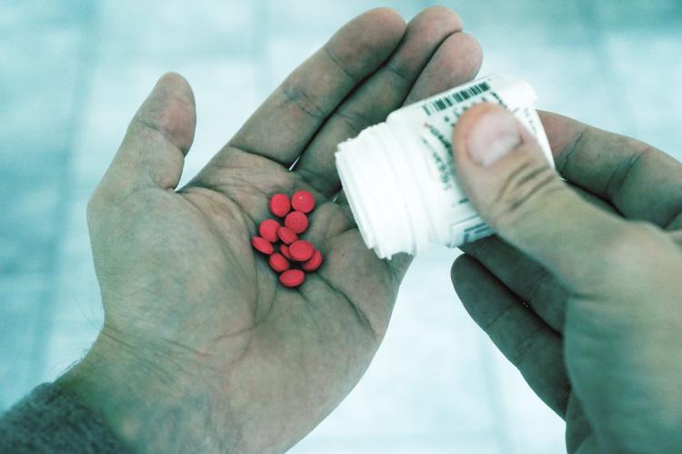 Man pouring pills out of bottle and into hand
