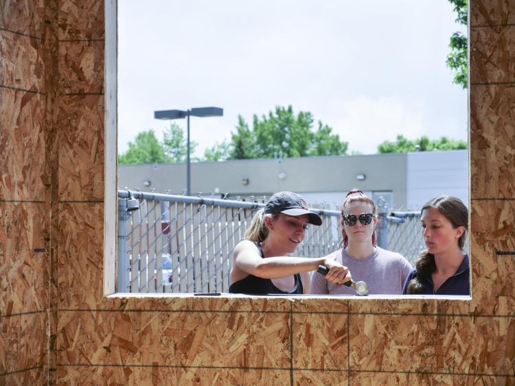 Three women work on the window of a pocket studio.