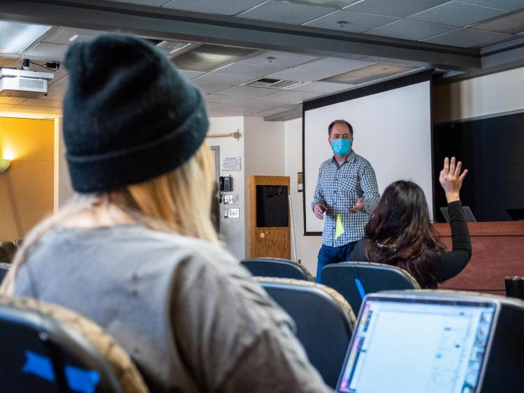 Students listen to lecturer while physically distancing