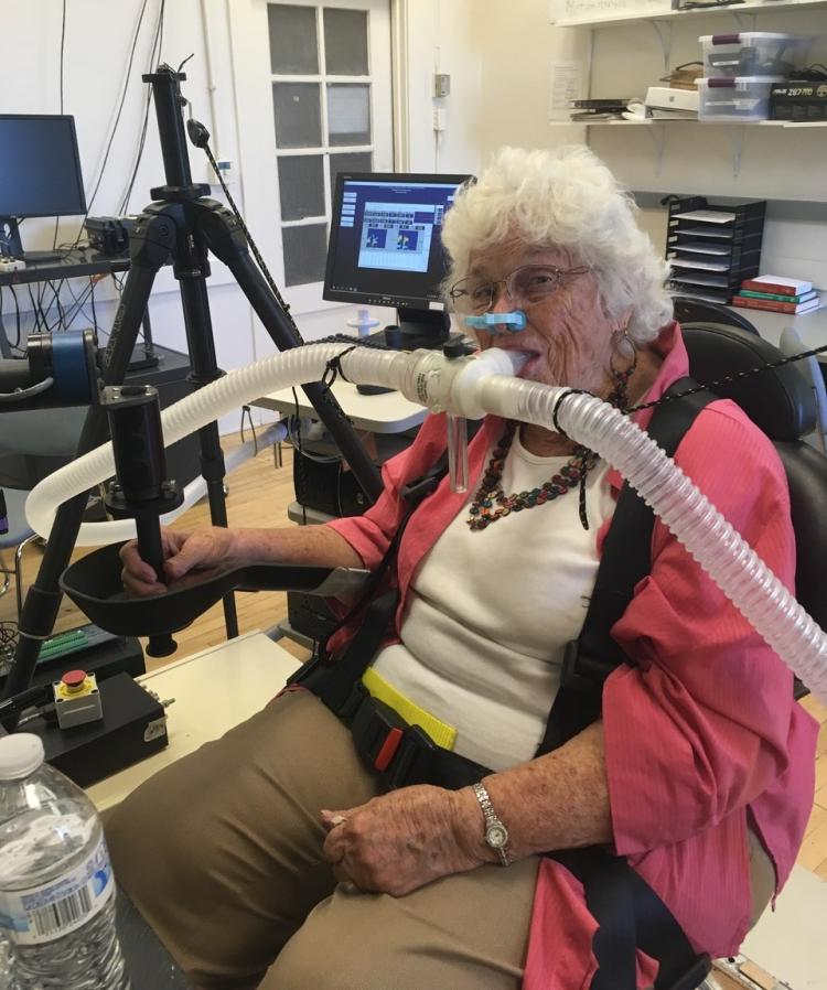 Woman sits in a chair with tubes connected to her nose and mouth