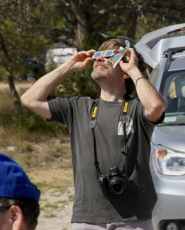 Kevin Reardon wearing eclipse glasses staring up