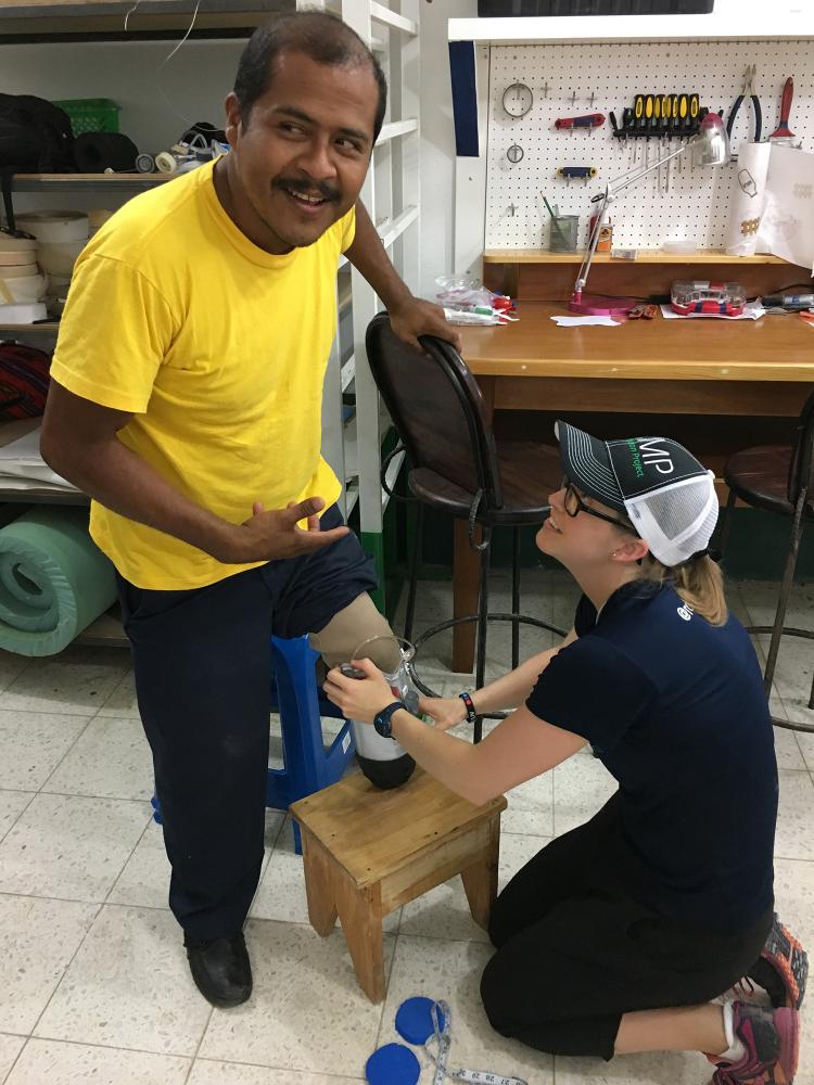 Madalyn Kern fits her prosthetic leg invention on a man