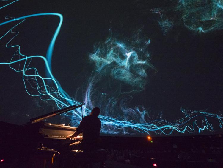 Roman Zavada performs live to lasers and footage of the Aurora Borealis in Northern Canada at Fiske Planetarium. Photo by Glenn Asakawa.