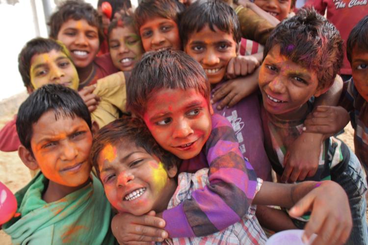 10 Kids in India with paint on their faces. Two in the front are hugging.