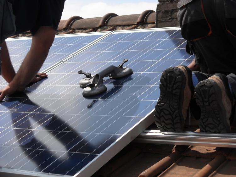 Workers install solar panels on a roof.
