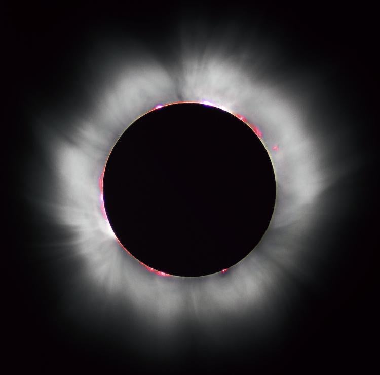 White lines of radiation emerge from the sun as its face lies in shadow during an eclipse
