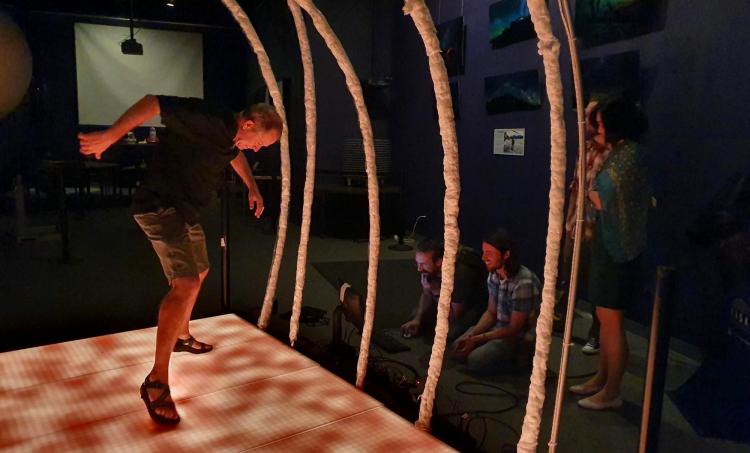 Fiske Planetarium Director John Keller tap dances on a visiualization of the surface of the sun while several students look on.