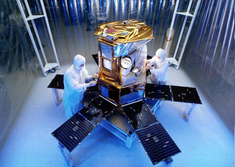 Technicians work on a spacecraft in a cleanroom