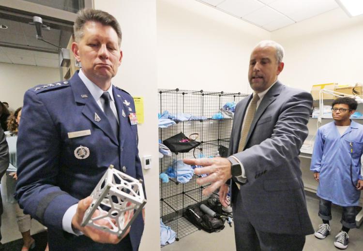 Scott Palo hands Gen. Thompson the frame for a CubeSat