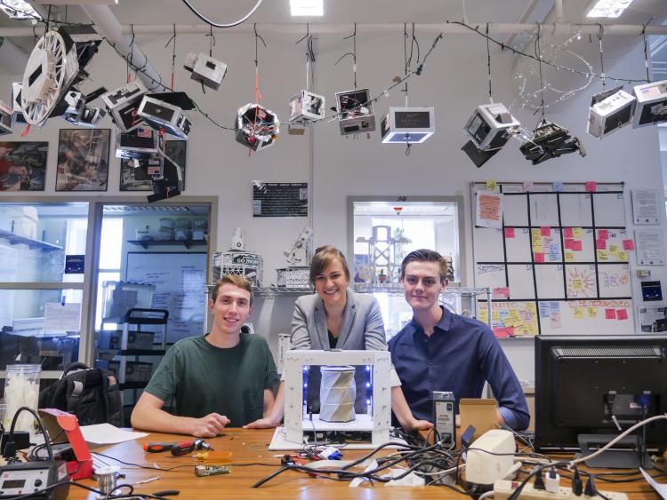 Andrew Pfefer, Anastasia Muszynski and Dawson Beatty pose with their inflatable, collapsable device with origami-type folds