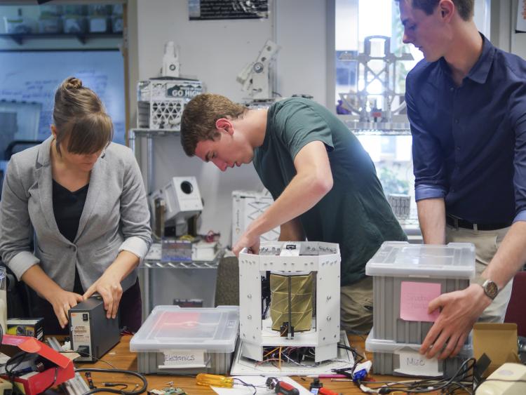 Anastasia Muszynski, Andrew Pfefer and Dawson Beatty work with their origami device