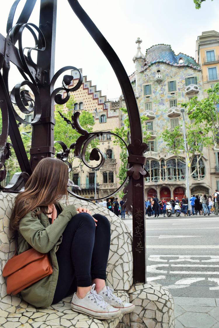 A woman sits on a set of mosaic stairs taking in the ornate architecture of Barcelona, Spain.