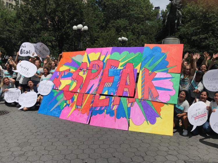 Girls hold signs saying 'Speak,' an example of an 'Ethical Spectacle'