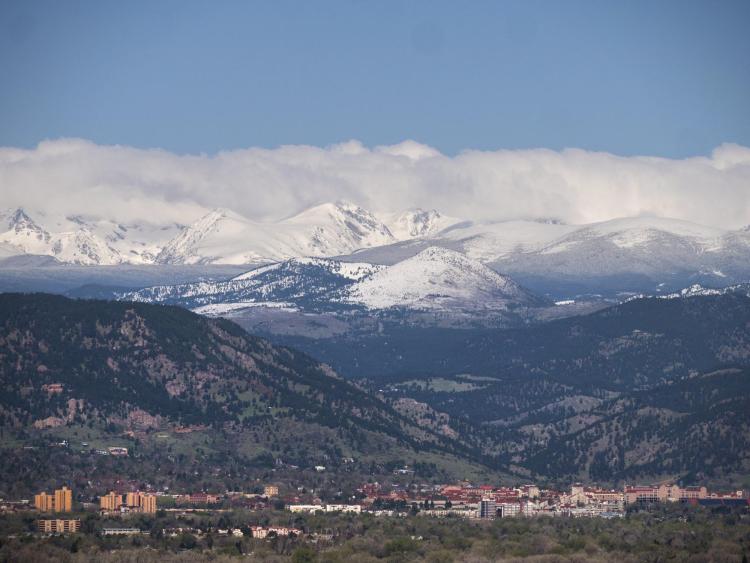 The CU Boulder campus with both green, spring mountains and snow-capped mountains. Photo by Glenn Asakawa.