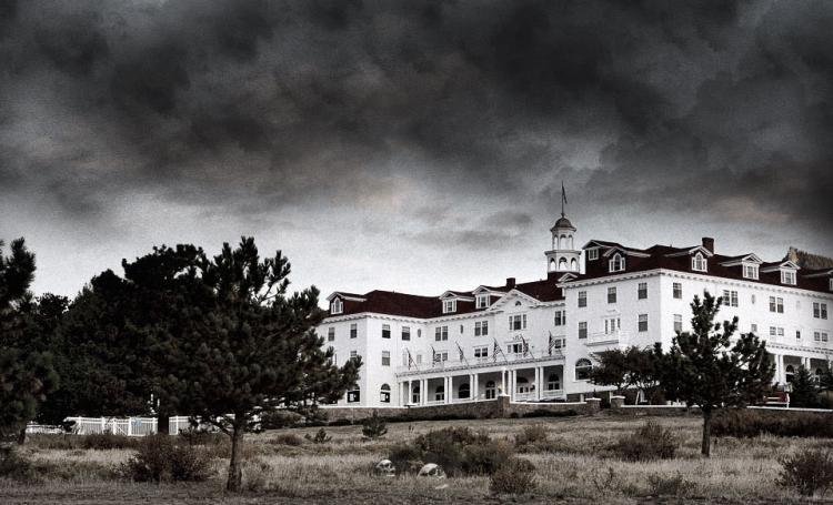 A black and white photo of the Stanley Hotel in Estes Park Colorado, with ominous black clouds in the background.
