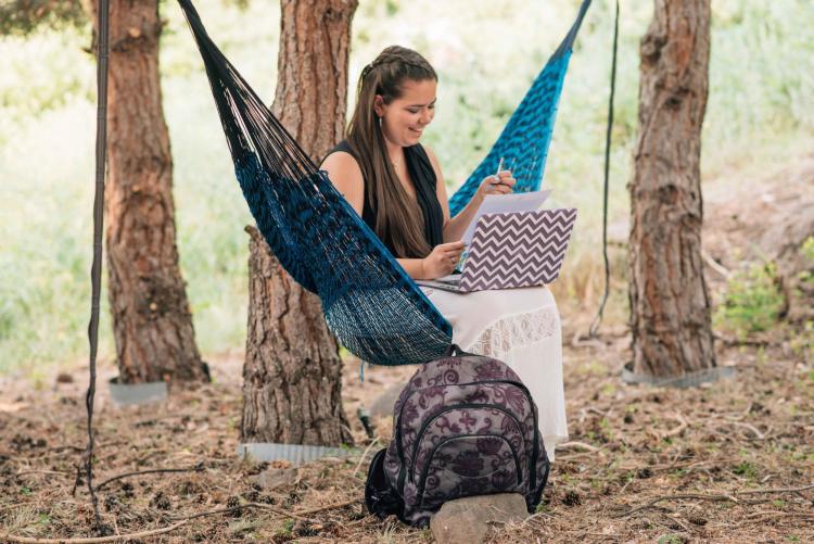 Student sits in hammock on campus while studying
