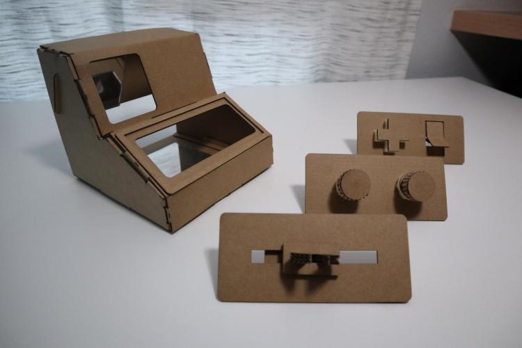 A Tinycade box sitting next to three cardboard controllers