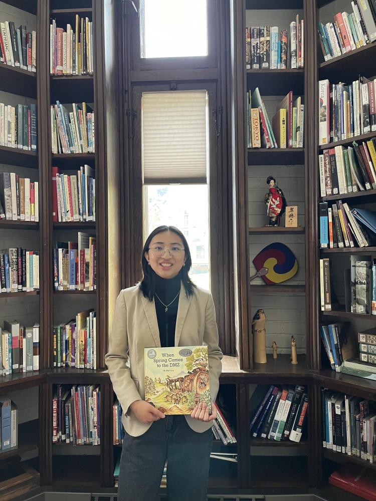 Valerie Lombogia showcases her assigned book after an online visit with a high school class
