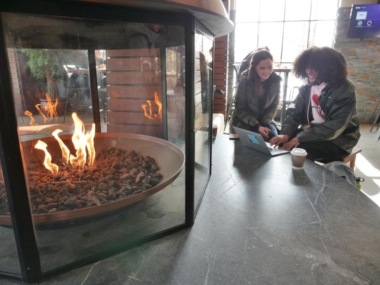 Students warm themselves on an extremely cold day at the WeatherTech Cafe fireplace