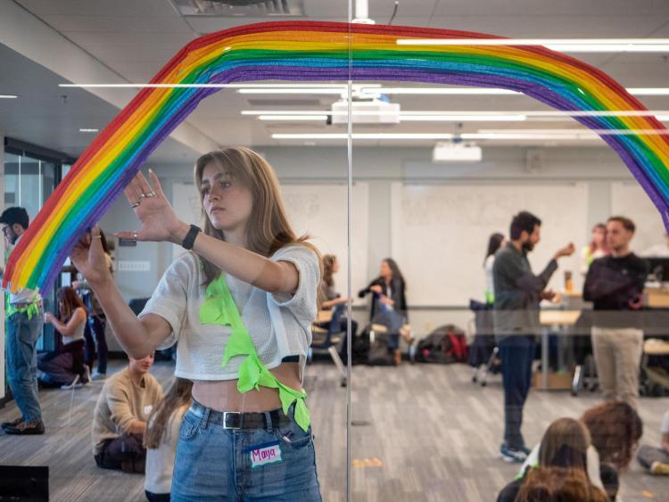 A student painting a rainbow on a window