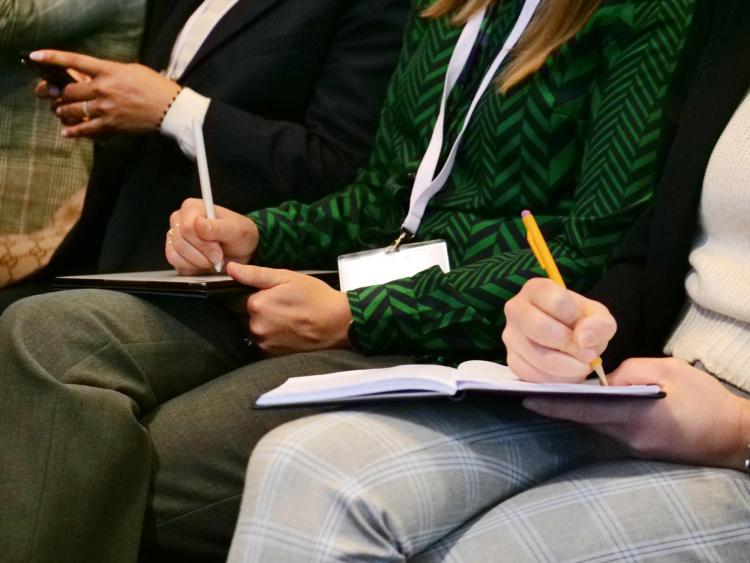 Attendees listen in and take notes during a speaker session