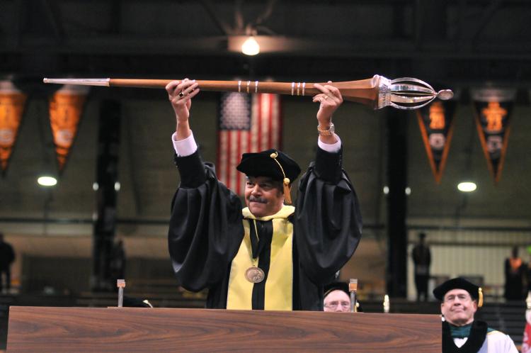 Jim Williams holds the university mace, or staff, during a commencement ceremony.