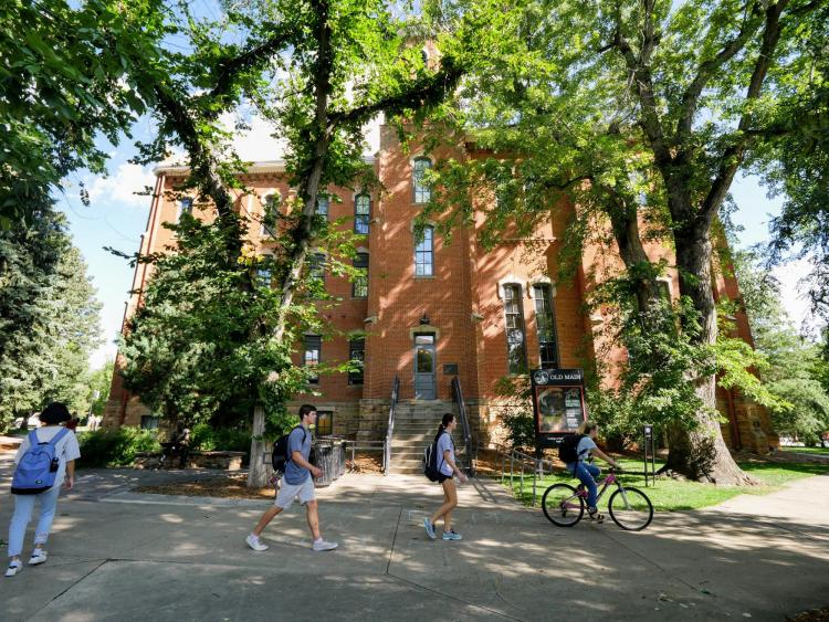 Campus community members walk past Old Main