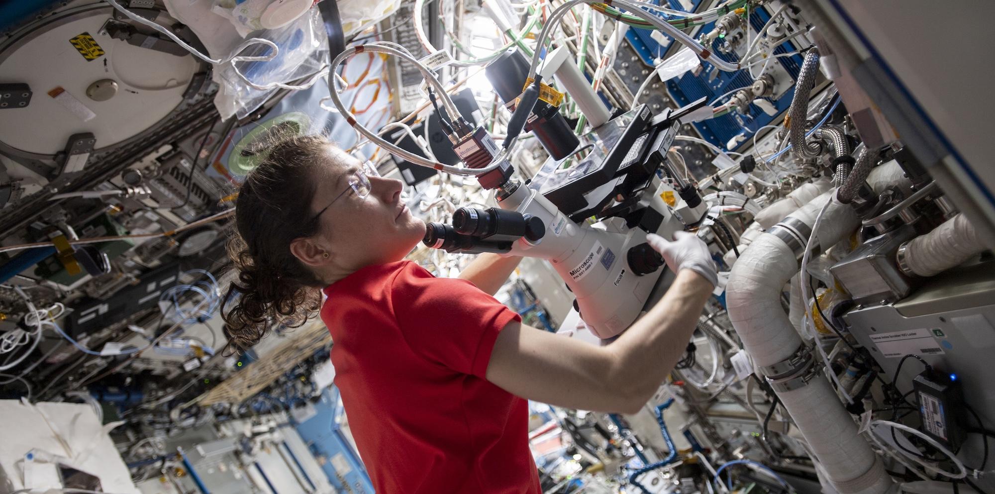 Astronaut in space station using scientific equipment
