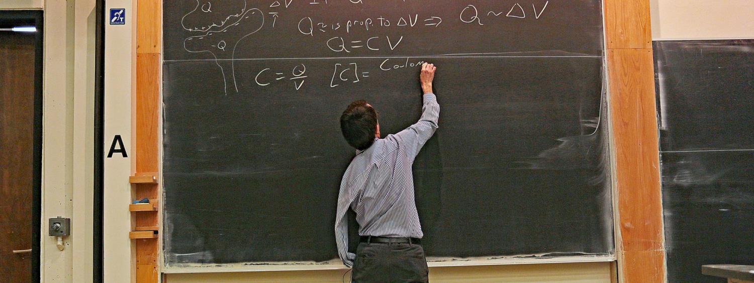 Physics professor writing on a blackboard in the classroom