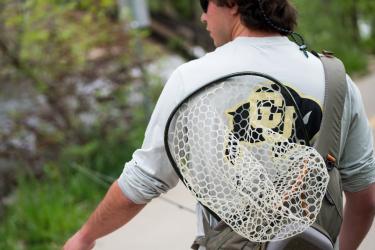 Ryan Watson walks along Boulder Creek with a fishing net