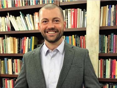 Zachary Owens in front of bookcases