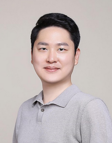 Man with black hair and grey polo shirt poses for portrait