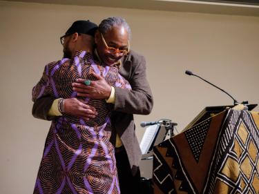 Thomas Windham and Reiland Rabaka embrace as Rabaka takes the stage after being introduced by Windham. (Glenn Asakawa/University of Colorado)