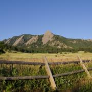 Wooden fence, green field and Flatirons