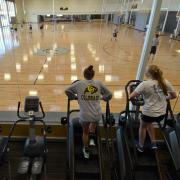 Students run on ellipticals while overlooking the basketball courts
