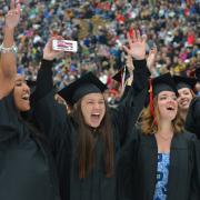 Girl raises hands in excitement during commencement