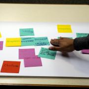 person places sticky note on poster during summit session