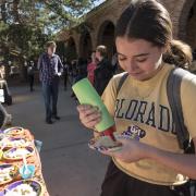 Student decorates a cookie at a campus event outdoors