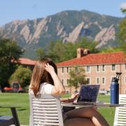 person works on laptop on campus