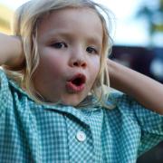 Little girl holds her hands over her ears