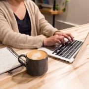 person working on laptop with a latte nearby